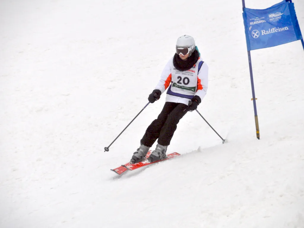 Skifahrer mit Startnummer 20 an einem blauen Tor.
